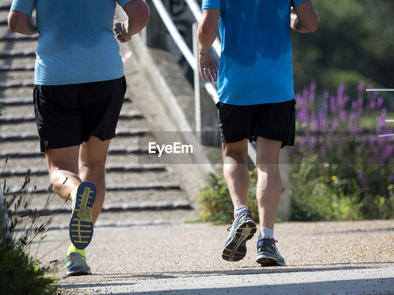 Low section of man and woman running on road