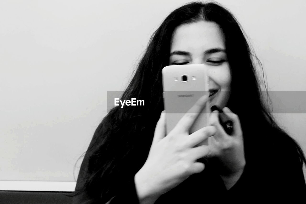 PORTRAIT OF A BEAUTIFUL YOUNG WOMAN WITH HAND HOLDING WALL