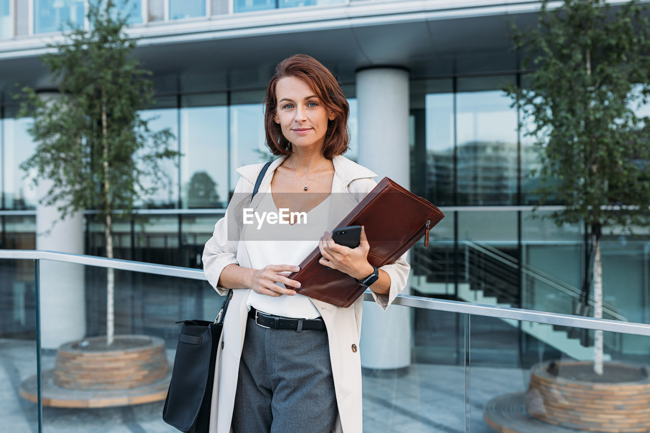 portrait of young woman using digital tablet while standing in city