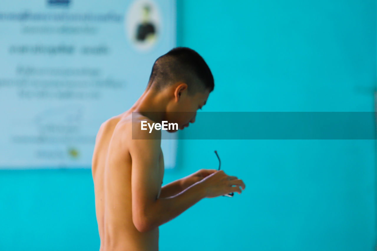 Side view of man holding eyeglasses at swimming pool