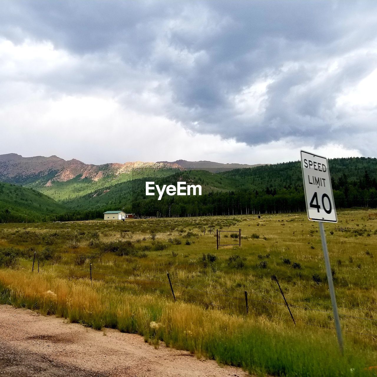 ROAD SIGN ON FIELD AGAINST CLOUDY SKY