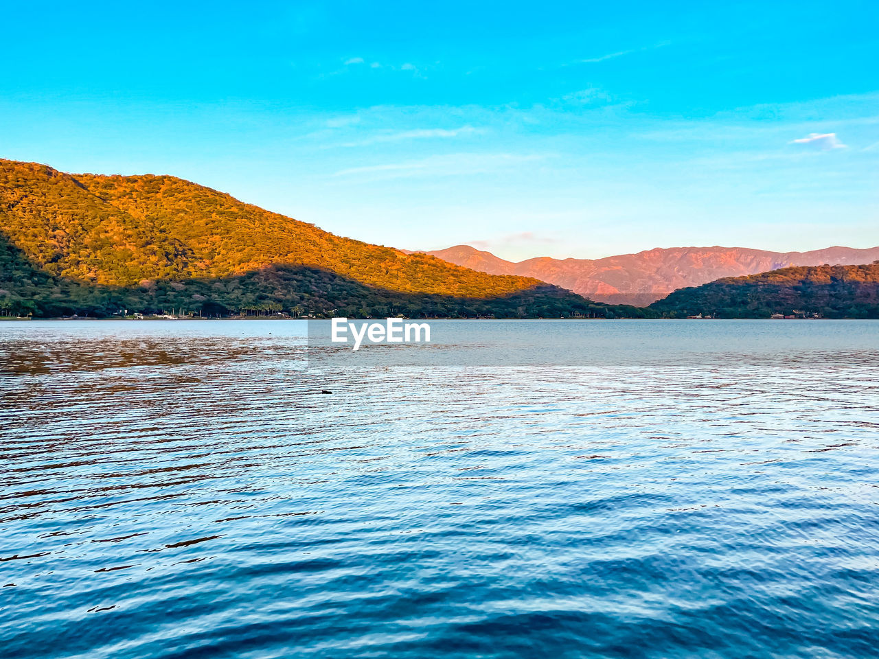 mountain, water, scenics - nature, sky, landscape, beauty in nature, lake, environment, nature, blue, land, no people, shore, mountain range, body of water, tranquil scene, tranquility, travel destinations, travel, horizon, outdoors, reflection, coast, day, cloud, clear sky, idyllic, dusk, sunlight, non-urban scene, reservoir, tourism, ocean