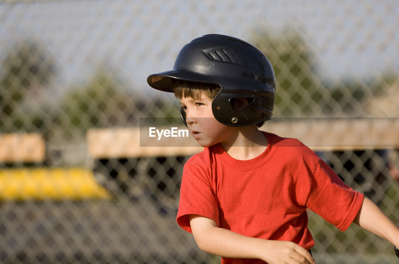 Young boy in baseball helmet concentrating on his hit