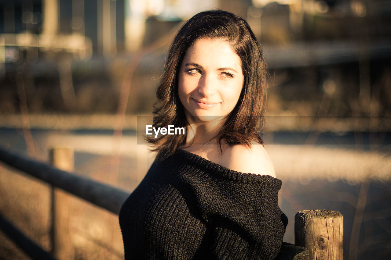 PORTRAIT OF SMILING WOMAN STANDING OUTDOORS