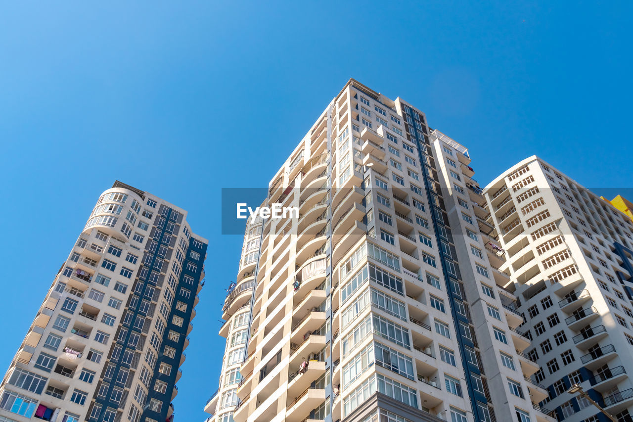 LOW ANGLE VIEW OF MODERN BUILDINGS AGAINST BLUE SKY