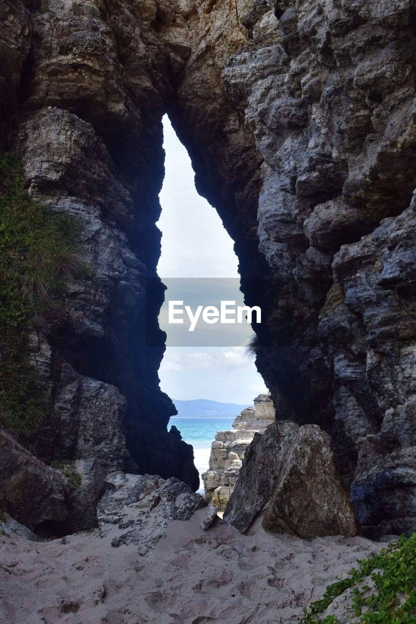 Rock formation by sea against sky