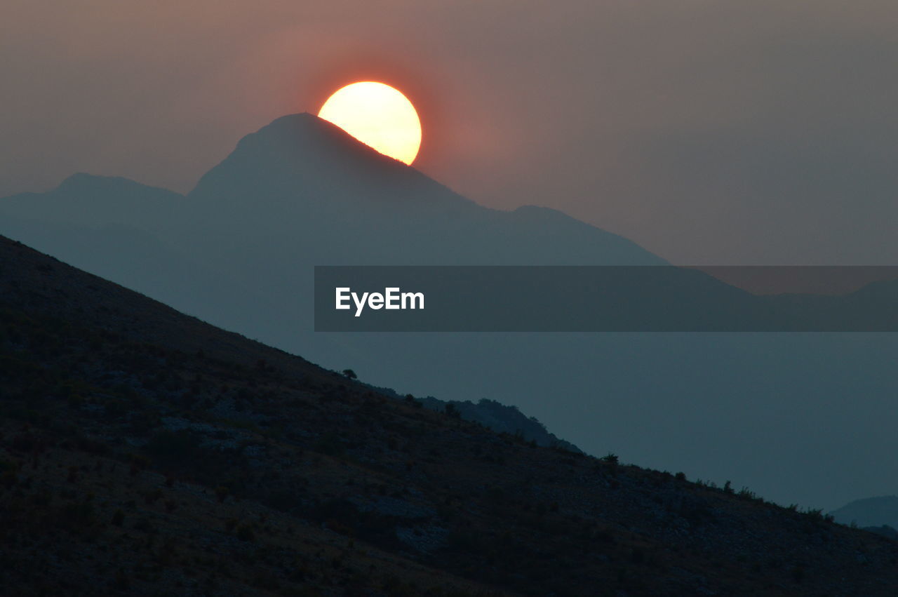 SCENIC VIEW OF MOUNTAINS AGAINST SKY AT SUNSET