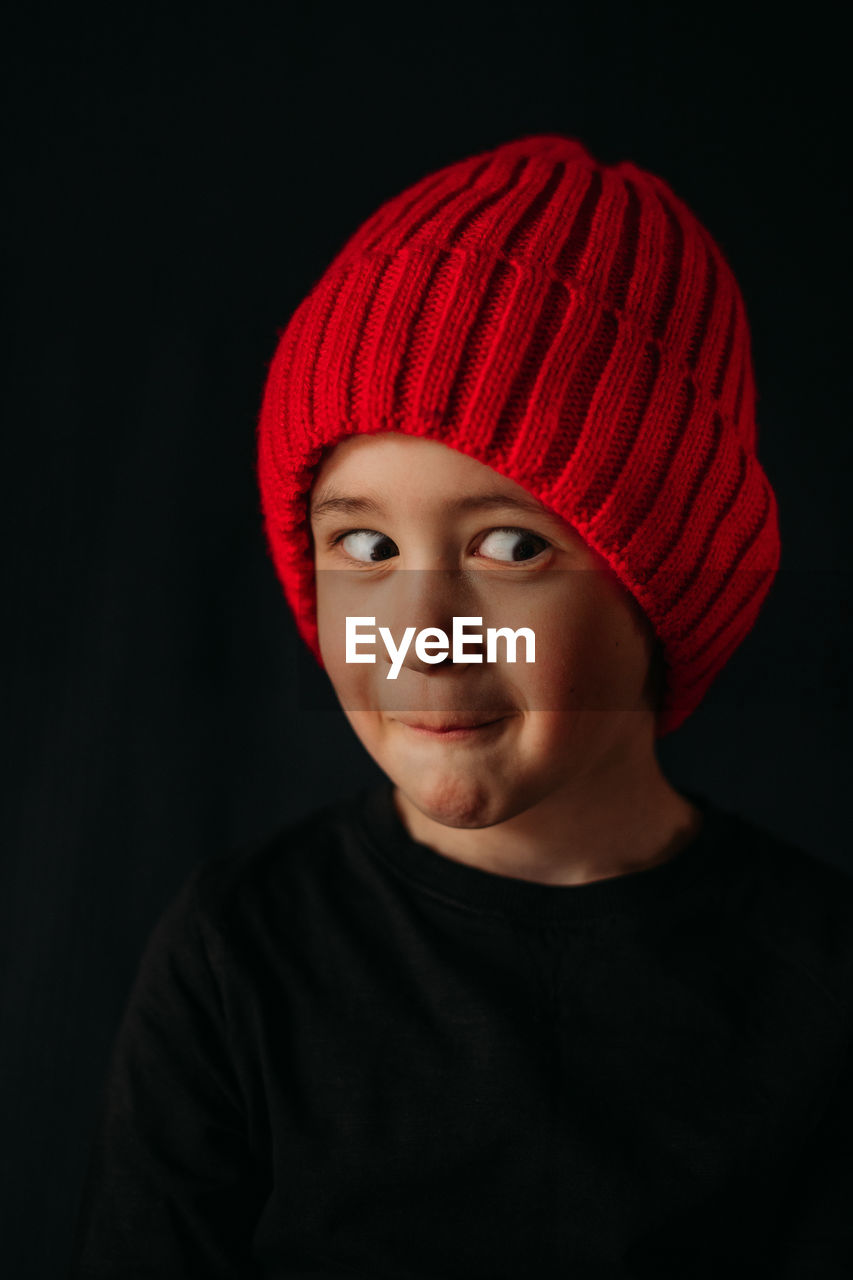 Portrait of boy wearing hat against black background