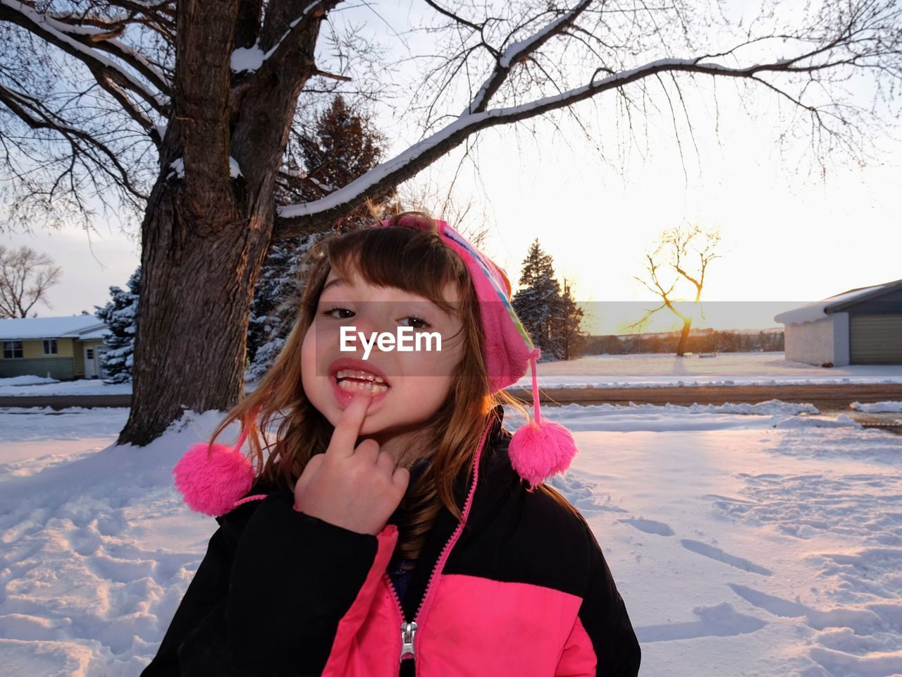 Portrait of girl showing finger on lips against snow during winter