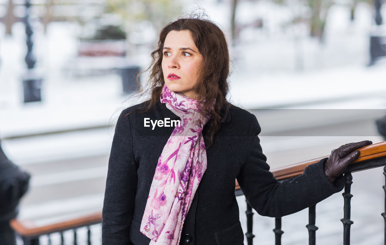 young woman looking away while standing outdoors