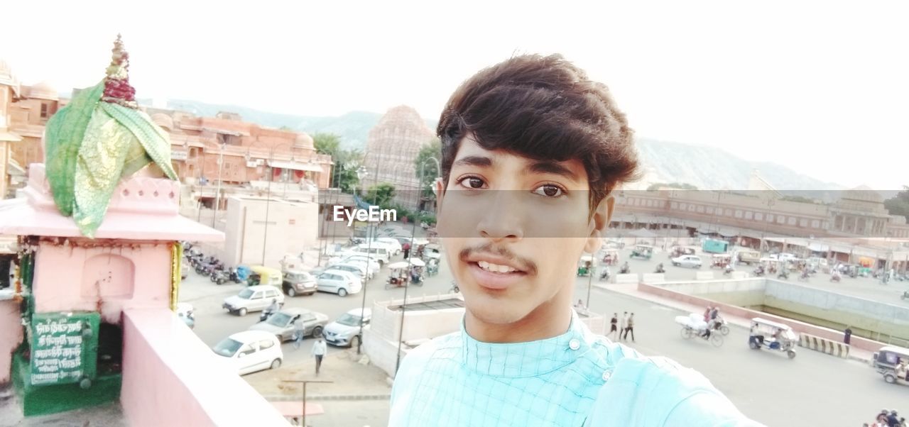 PORTRAIT OF SMILING MID ADULT MAN IN CITY AGAINST CLEAR SKY