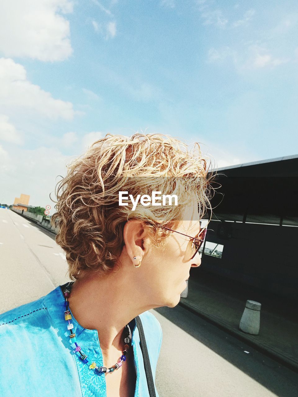 Close-up of woman looking away against sky on sunny day