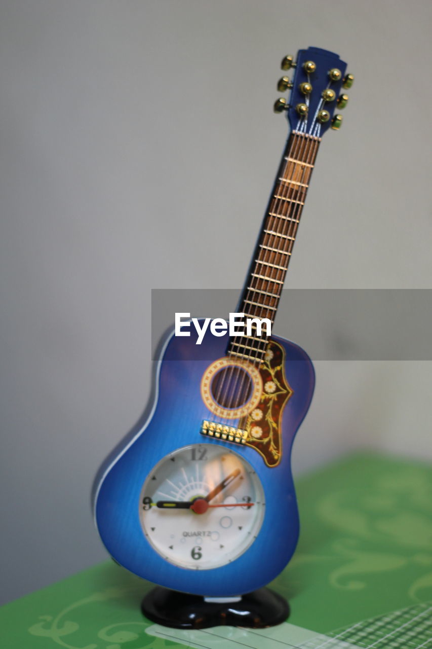Close-up of toy guitar clock against gray background
