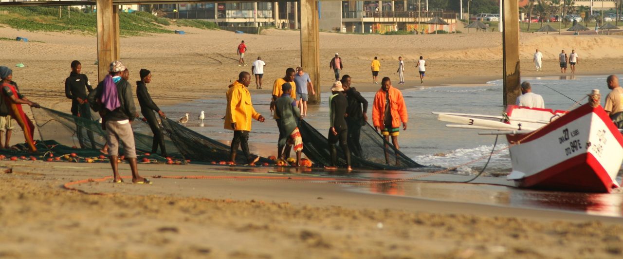 Panoramic view of fishermen working on sea shore