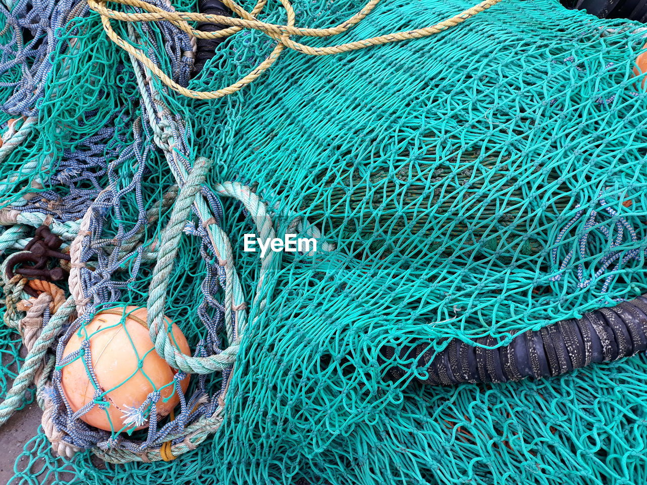 HIGH ANGLE VIEW OF FISHING NET AT BLUE ROPE