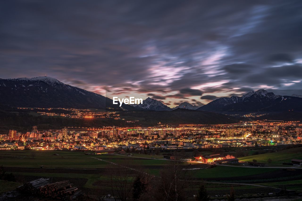 Illuminated cityscape against sky during sunset