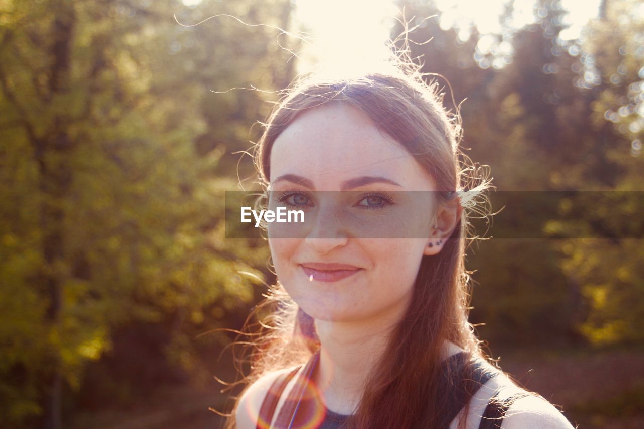 Portrait of young woman smiling while standing in forest