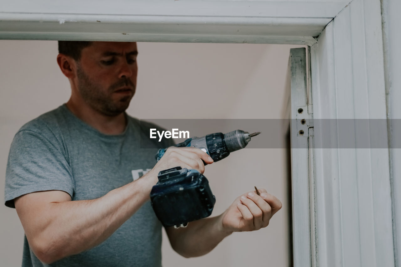 A young man with a drill in his hands.