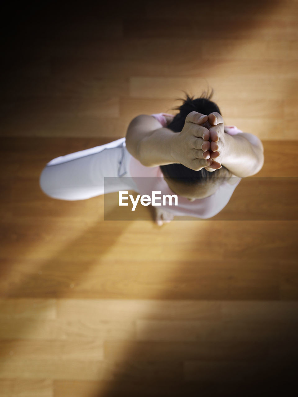 Directly above shot of woman practicing yoga on hardwood floor