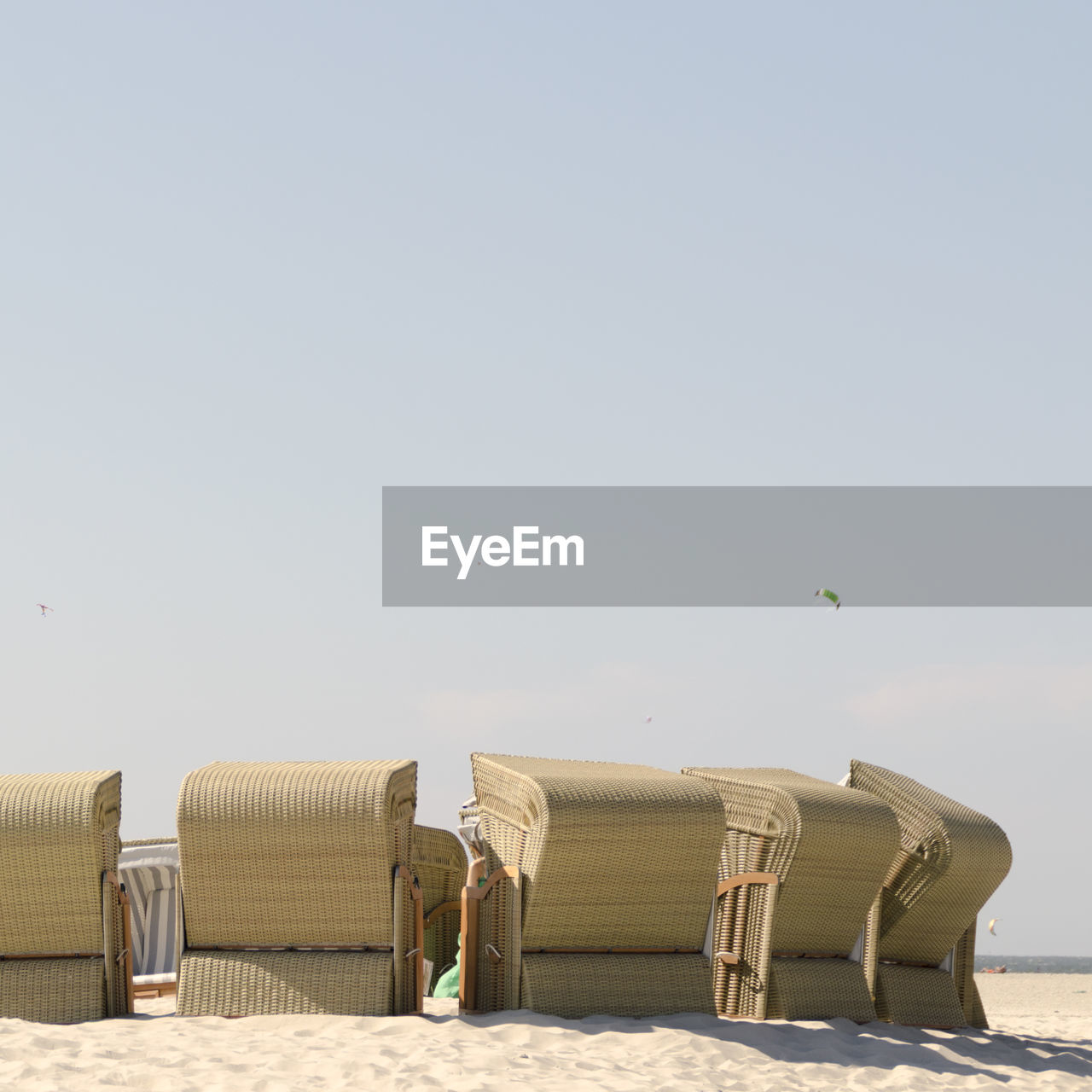 Hooded chairs on beach against clear sky