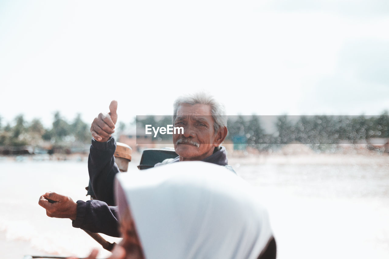 Portrait of man showing thumbs up against clear sky