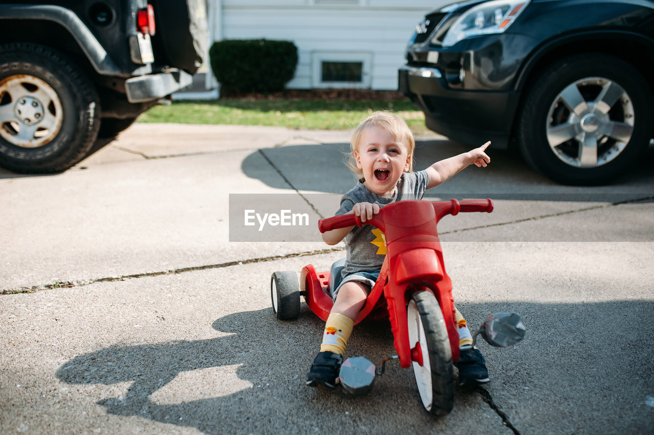 Young boy riding bike on driveway outside in summer