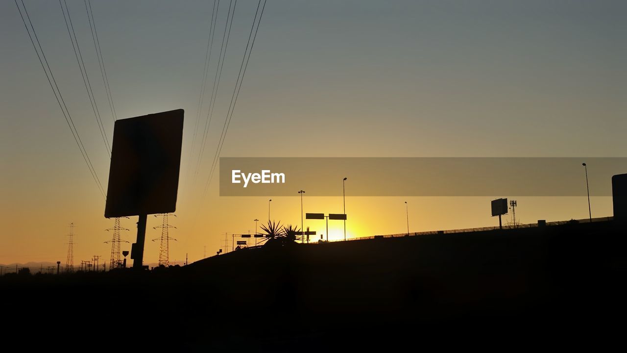 Silhouette signboards against clear sky during sunset