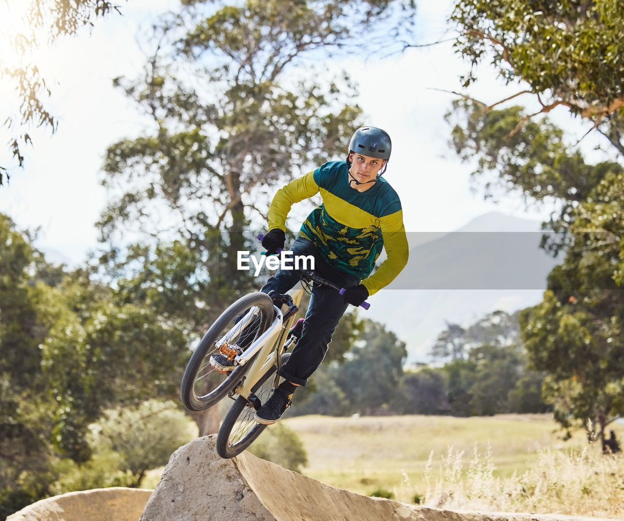 sports, cycle sport, bicycle, one person, mountain biking, helmet, skill, headwear, leisure activity, full length, motion, mountain bike, adult, downhill mountain biking, activity, men, extreme sports, nature, tree, bicycle motocross, lifestyles, day, vehicle, sports helmet, sports clothing, sports equipment, vitality, plant, adventure, clothing, exercising, young adult, stunt, transportation, land vehicle, outdoors, concentration, cycling, protection, risk, bmx bike, jumping, mid-air, agility, riding, challenge, sunlight, balance, determination, low angle view, cycling helmet, bmx cycling, speed, recreation, competition, front view, exhilaration, on the move, sky, joy, land, person