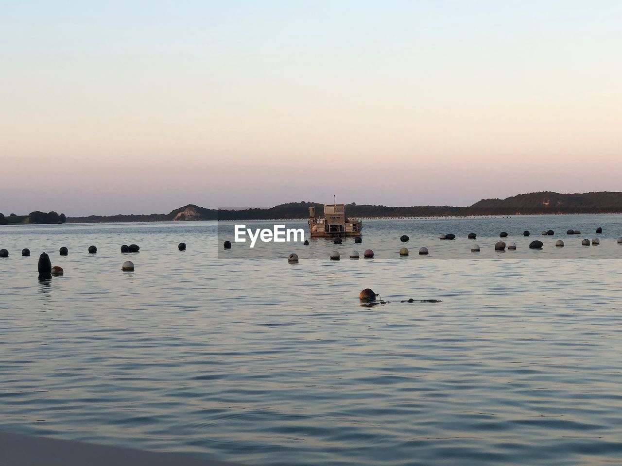 DUCKS SWIMMING IN LAKE AGAINST SKY AT SUNSET