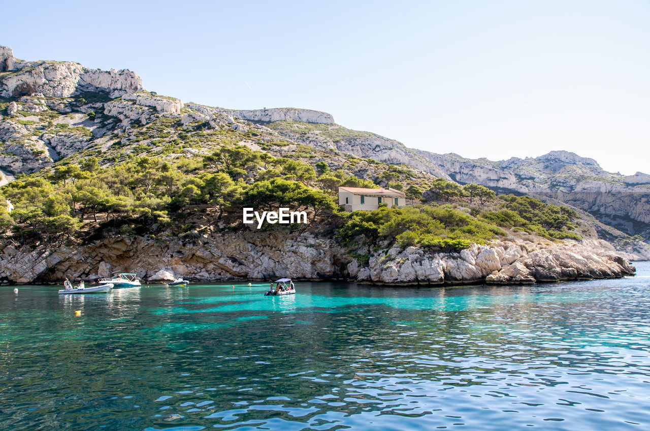 Scenic view of mountains by sea against clear sky