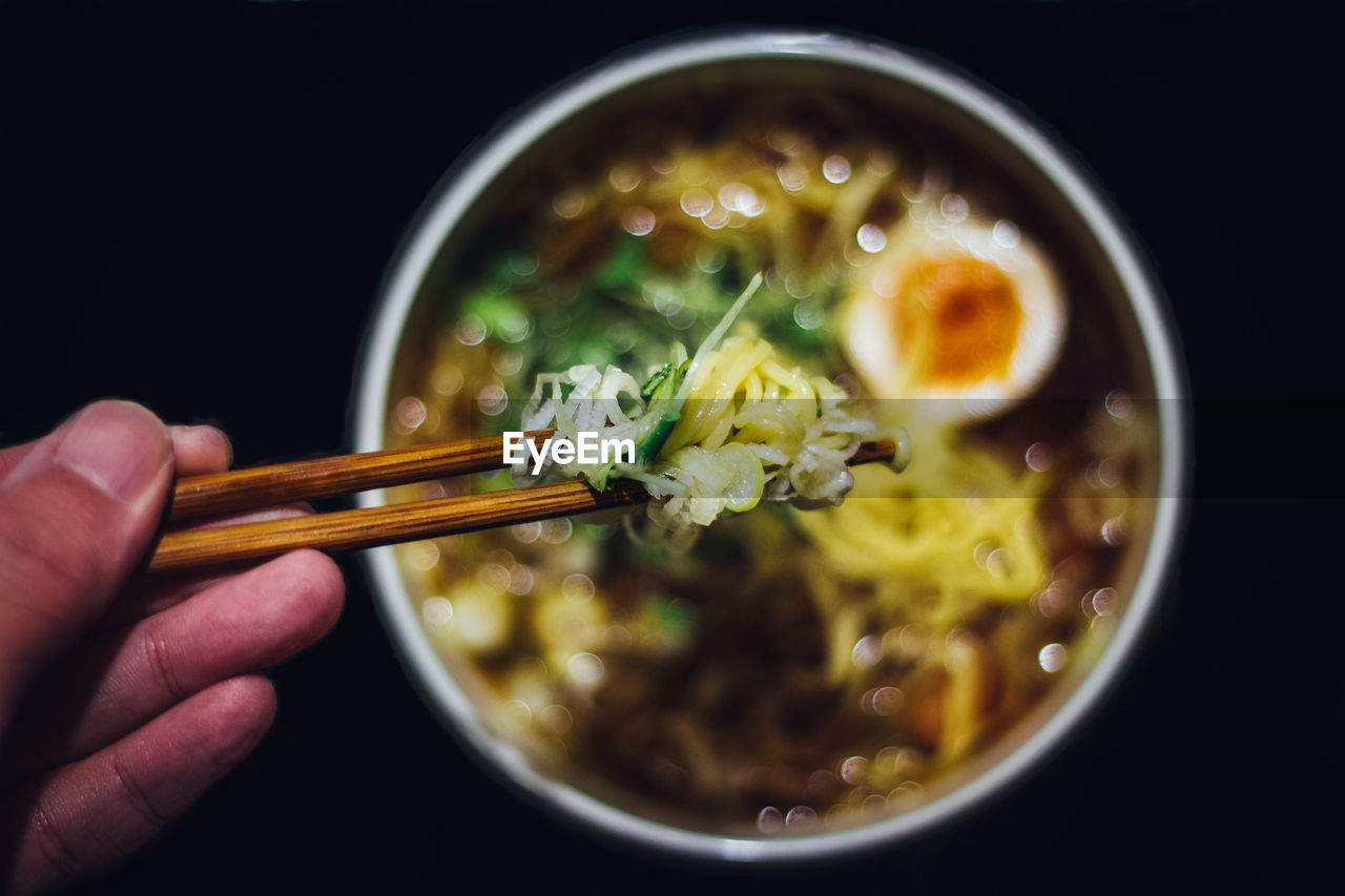 human hand, hand, food, food and drink, freshness, healthy eating, bowl, one person, human body part, ready-to-eat, holding, unrecognizable person, chopsticks, real people, indoors, close-up, wellbeing, lifestyles, soup, asian food, finger, japanese food, black background