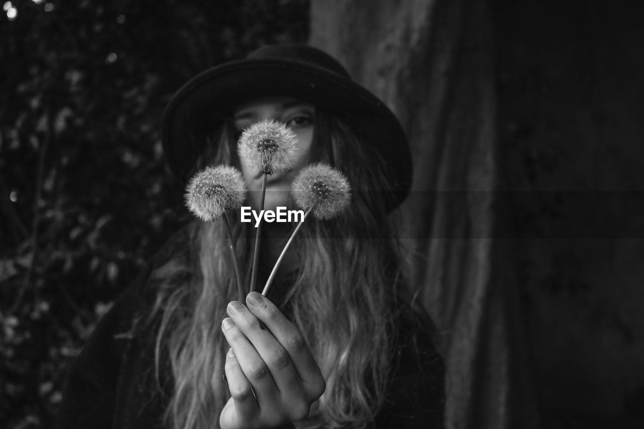 Portrait of woman holding dandelion