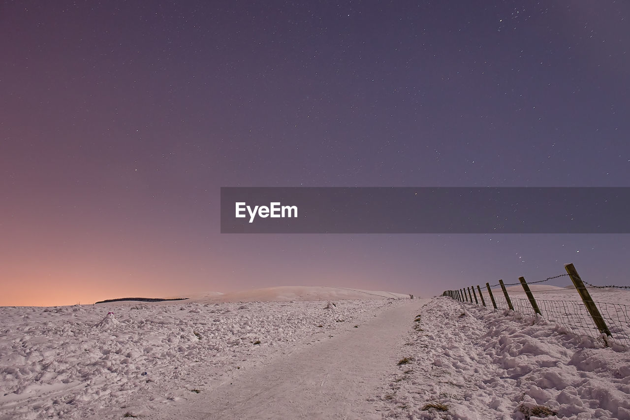 Scenic view of snowy landscape against clear sky at night