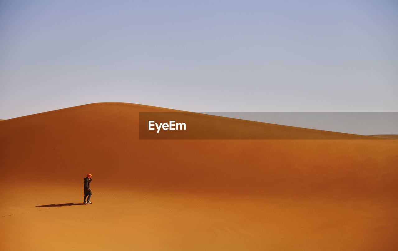 Man standing on desert against clear sky