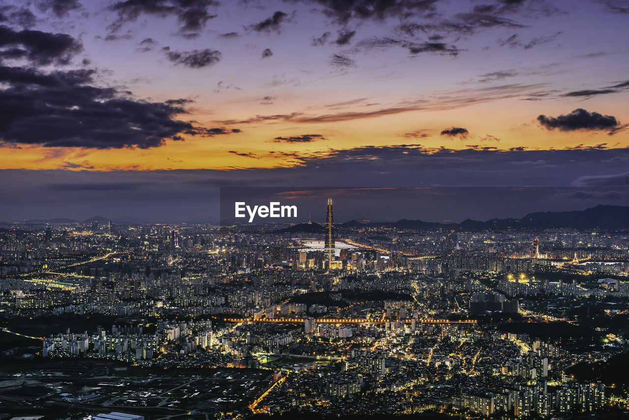 Aerial view of illuminated city buildings during sunset