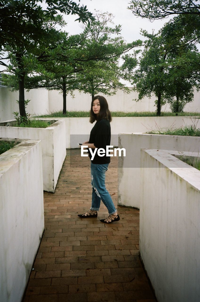 YOUNG WOMAN STANDING ON PARK