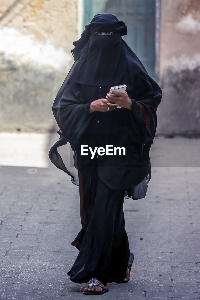 Rear view of woman standing on footpath