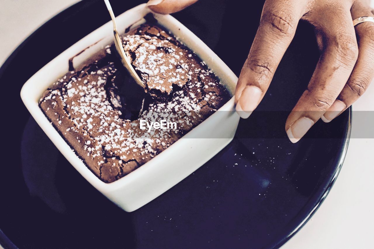 Cropped hand of woman holding sweet food in bowl at table