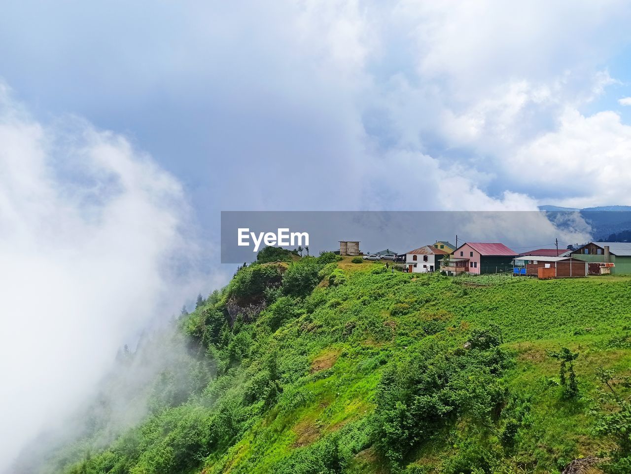 cloud, hill, sky, environment, landscape, architecture, land, nature, building, built structure, plant, house, building exterior, scenics - nature, mountain range, beauty in nature, rural scene, rural area, green, travel, no people, outdoors, residential district, hut, coast, sea, travel destinations, social issues, day, tourism, tree, field, agriculture, water, fog, village, non-urban scene, farm, growth