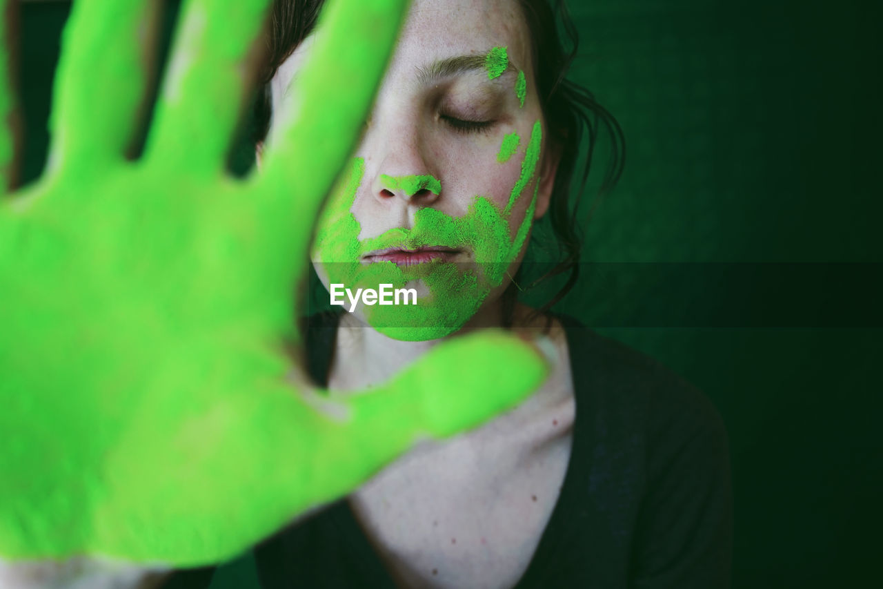Close-up of woman gesturing with green hand