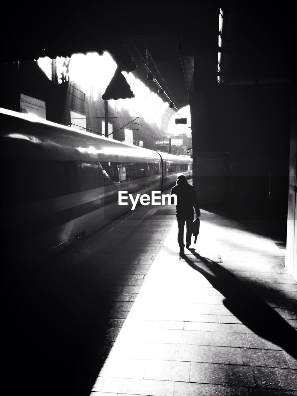 Silhouette of person walking on railroad station platform