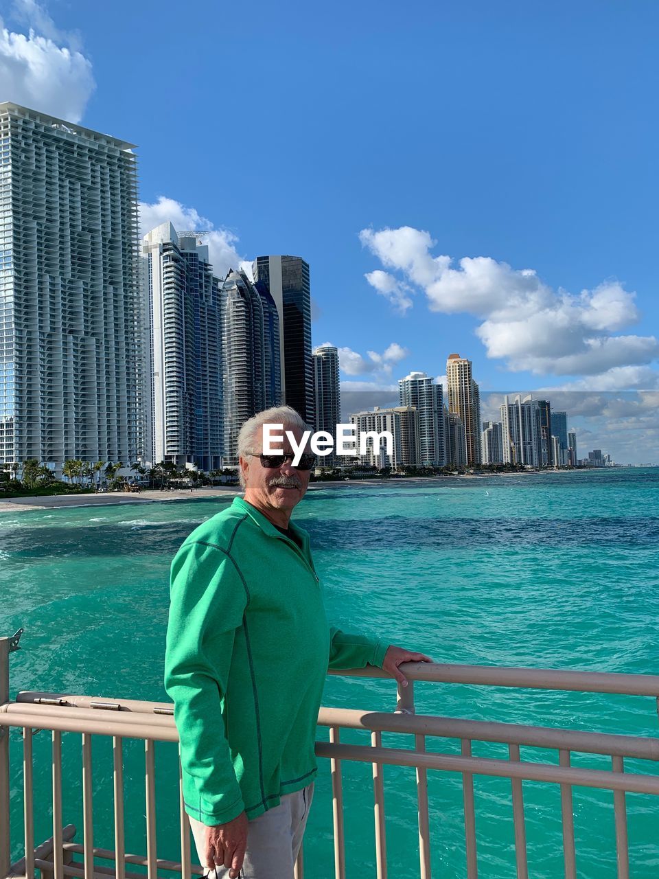 Portrait of man standing by sea against city