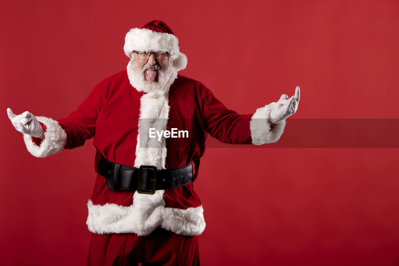 Santa claus making a rocker gesture on a red background