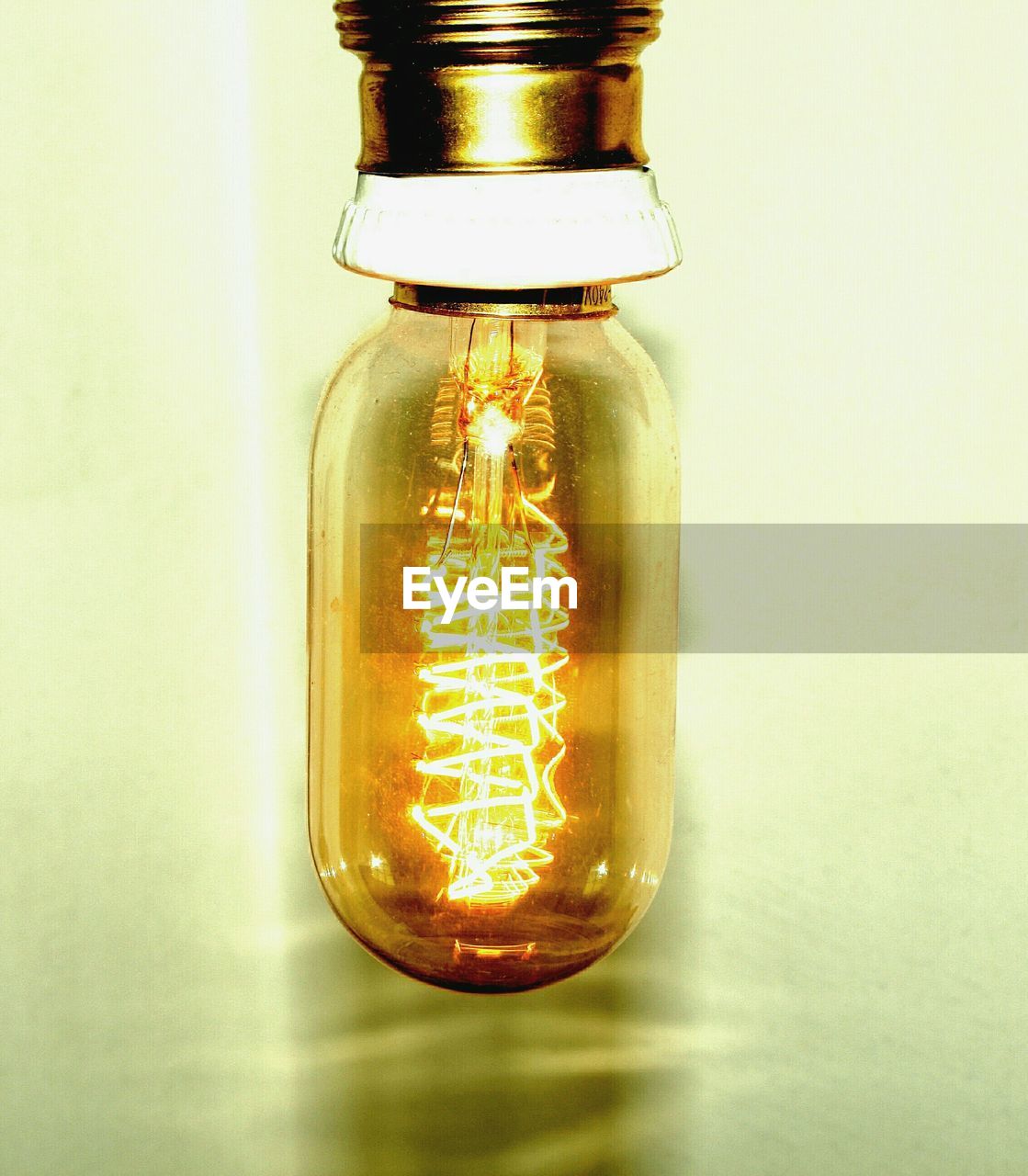 Close-up of illuminated light bulb against white background