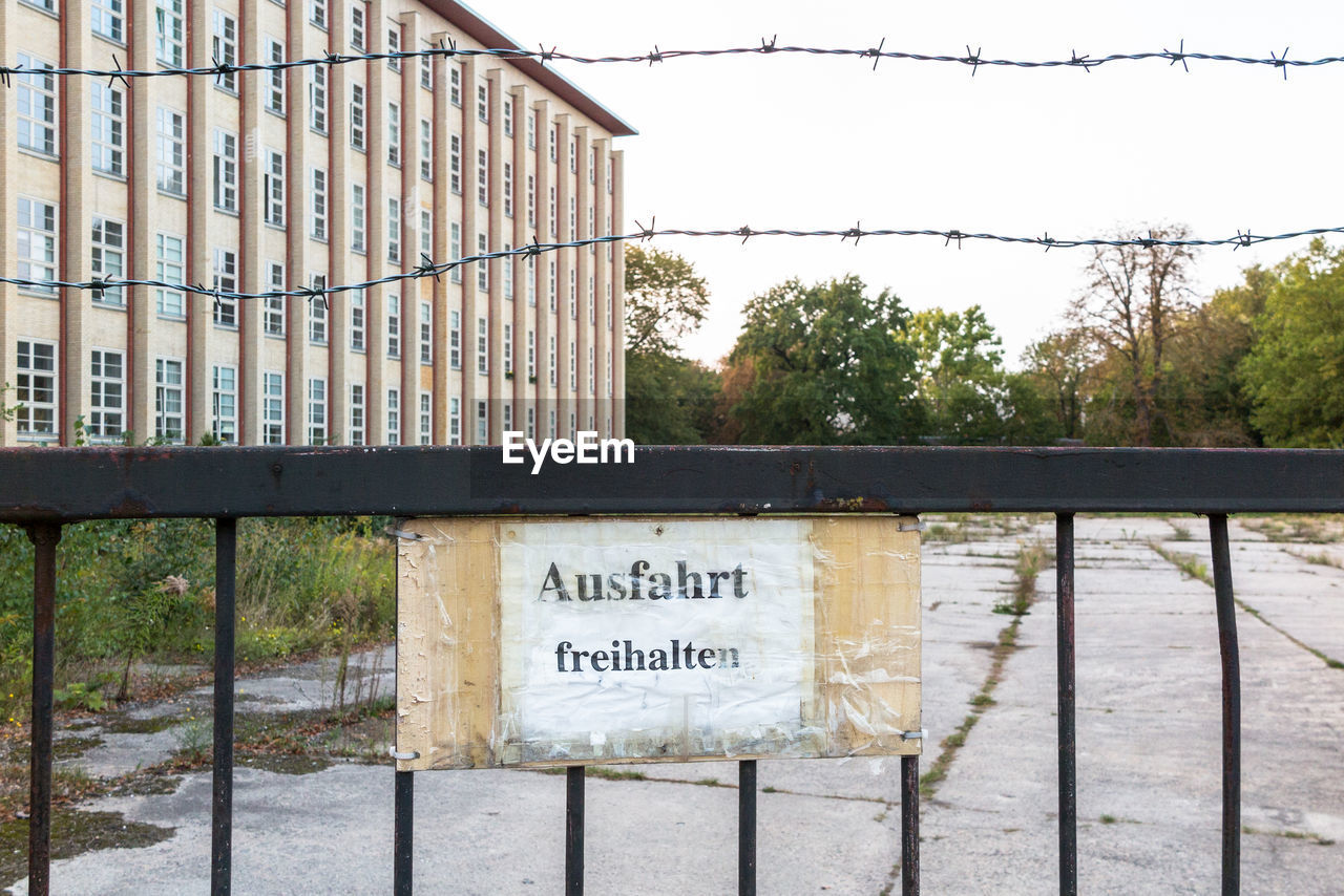 Signboard and barbed wire on fence against building