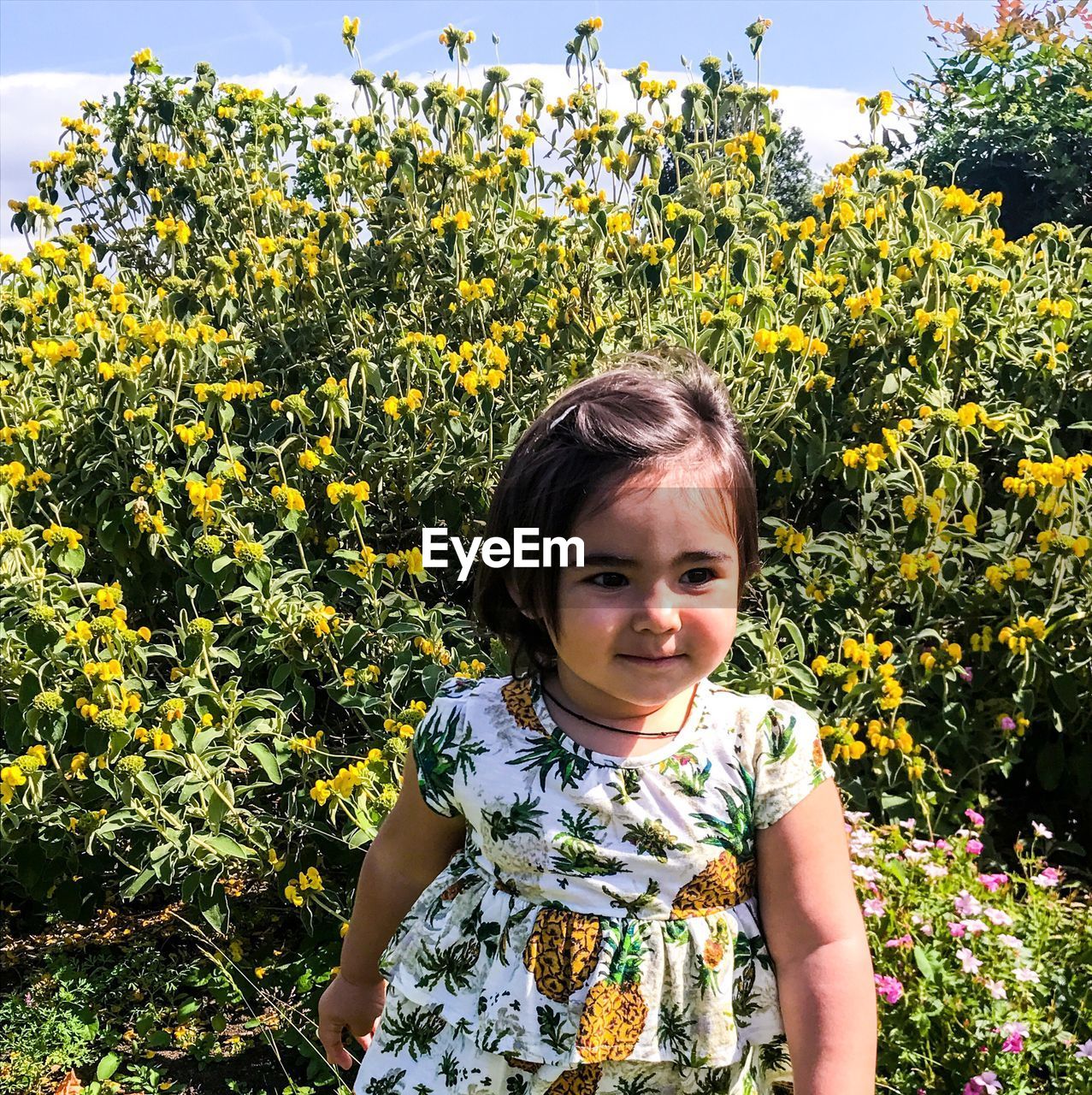 Cute girl looking away while standing by plants