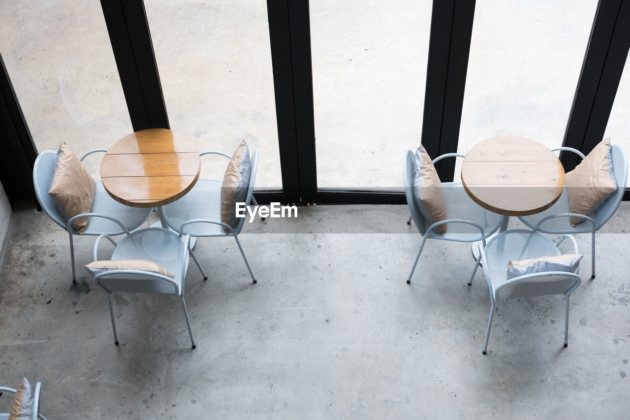 HIGH ANGLE VIEW OF CHAIRS ON TABLE AGAINST WINDOW