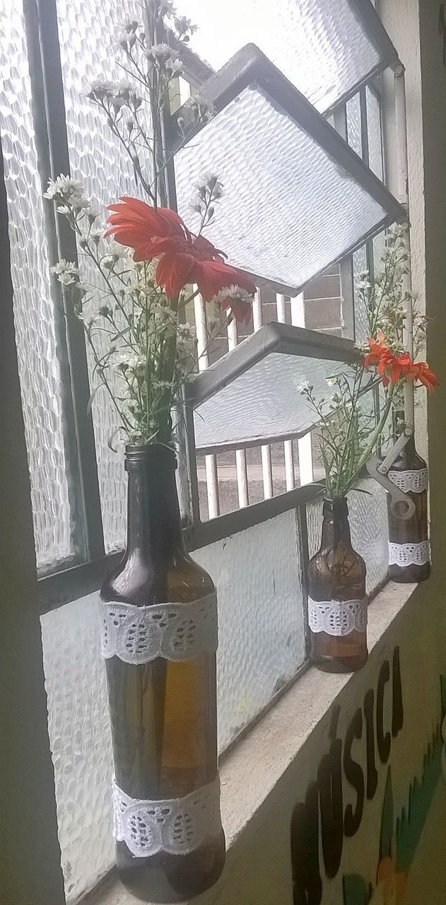 CLOSE-UP OF FLOWER ON TABLE AGAINST WINDOW