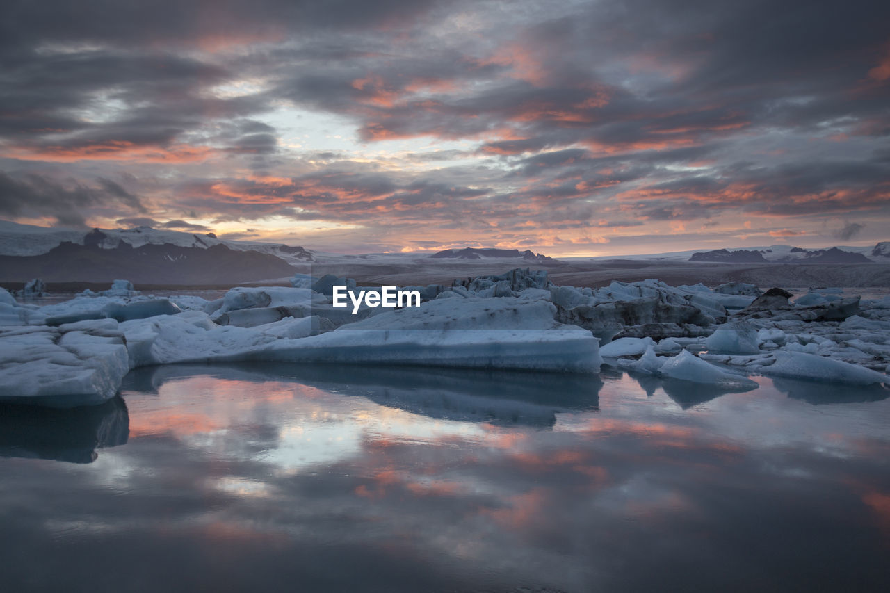 Scenic view of icebergs in lake against sky during sunset