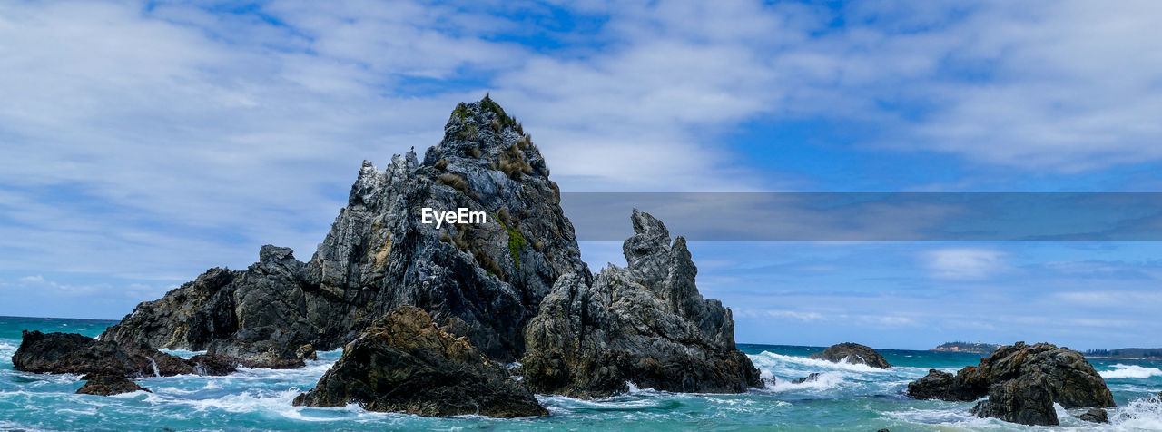 Rock formation on beach against sky